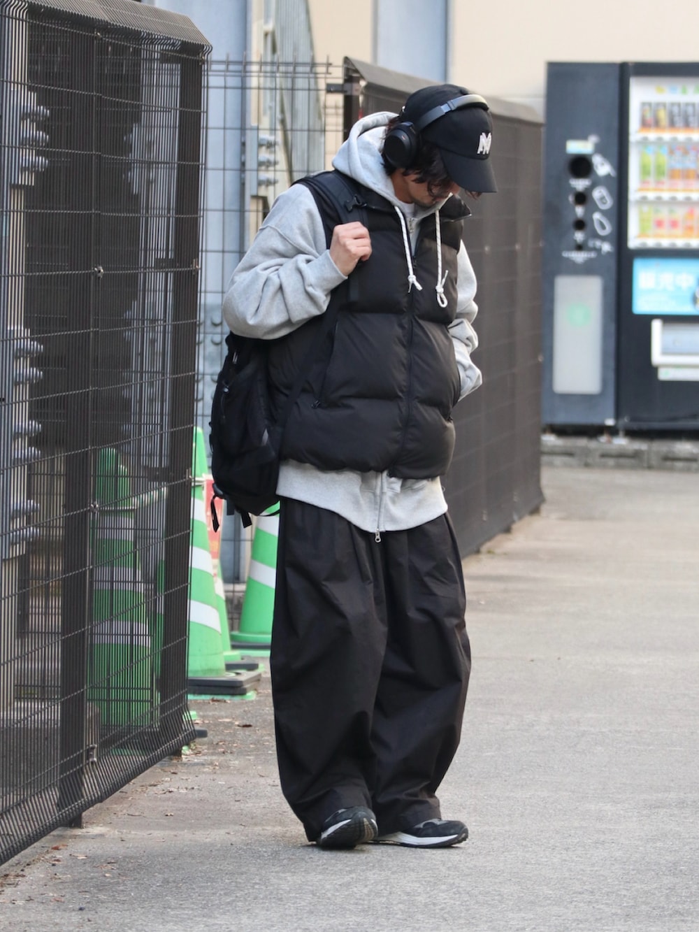 ブラック系のダウンベスト、グレー系のパーカー、ブラック系のチノパンツを着用したメンズの冬コーディネートの2枚目の写真