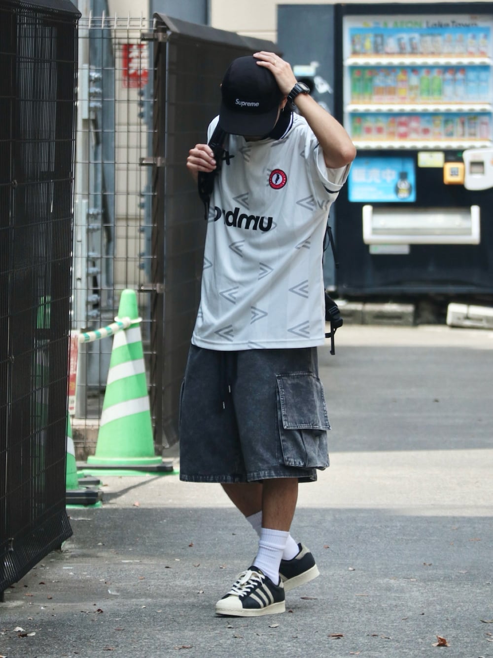 ホワイト系のTシャツ/カットソー、ブラック系のカーゴパンツ、ブラック系のスニーカーを着用したメンズの夏コーディネートの2枚目の写真