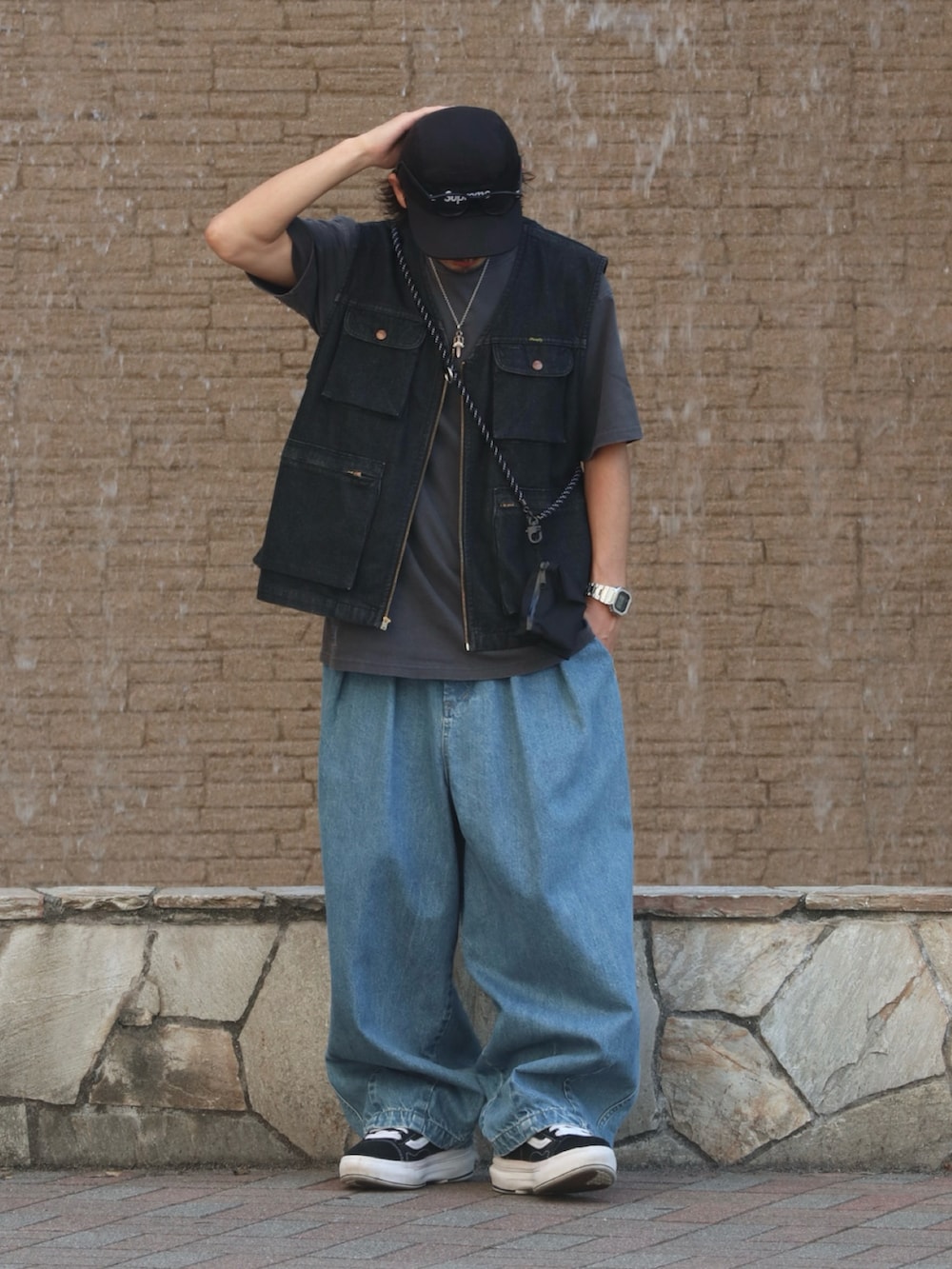 ブルー系のデニムパンツ、ブラック系のベスト、シルバー系のピアス（片耳用）を着用したメンズの夏コーディネートの2枚目の写真