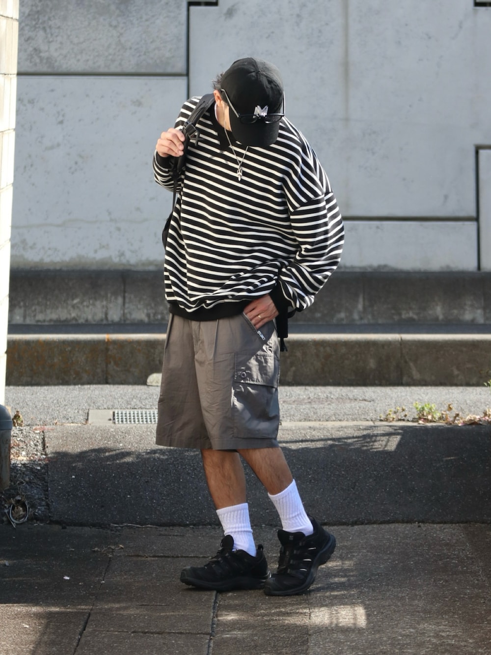 グリーン系のカーゴパンツ、ブラック系のスニーカー、シルバー系のピアス（片耳用）を着用したメンズの春コーディネートの2枚目の写真