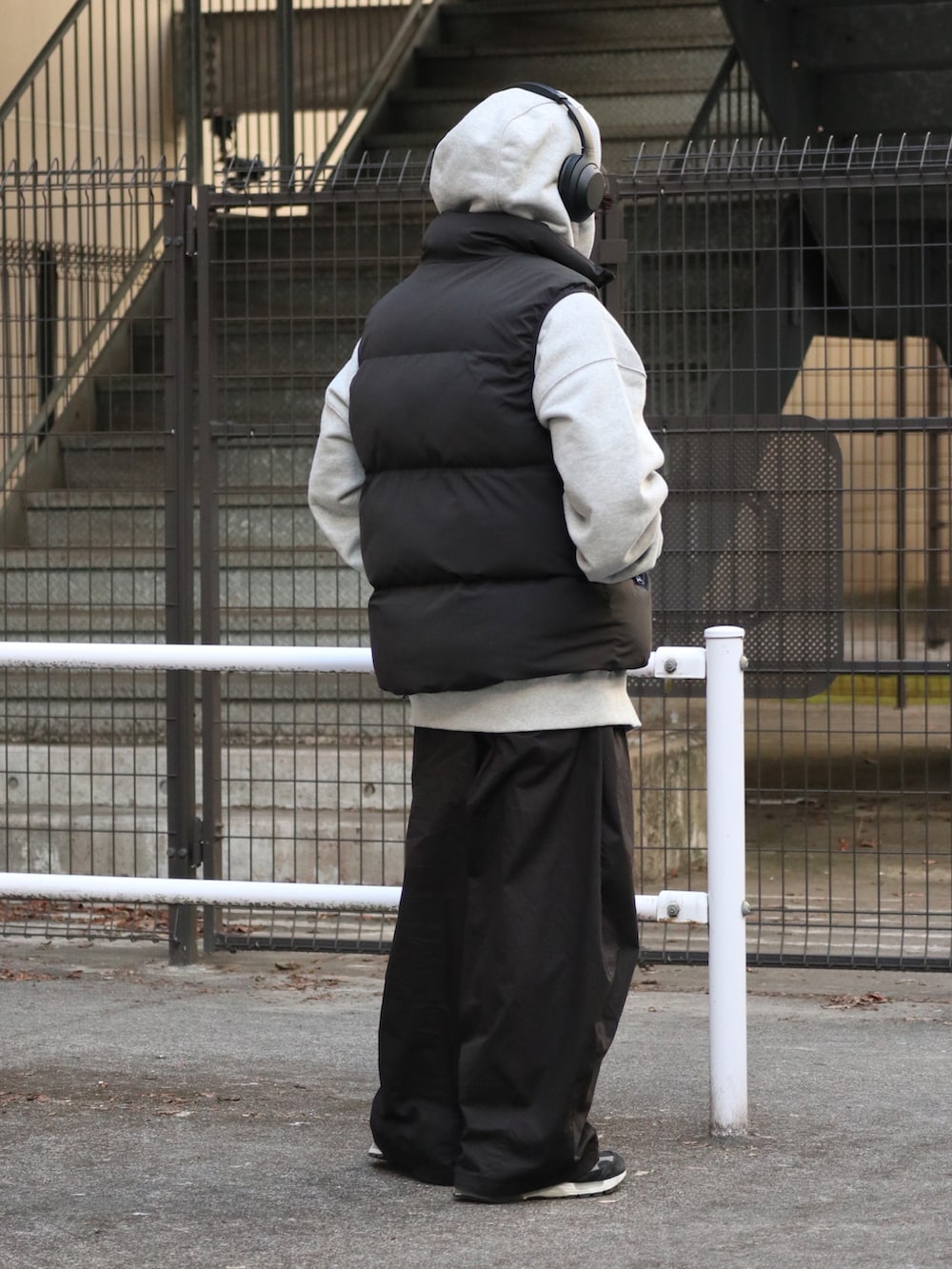 ブラック系のダウンベスト、グレー系のパーカー、ブラック系のチノパンツを着用したメンズの冬コーディネートの4枚目の写真