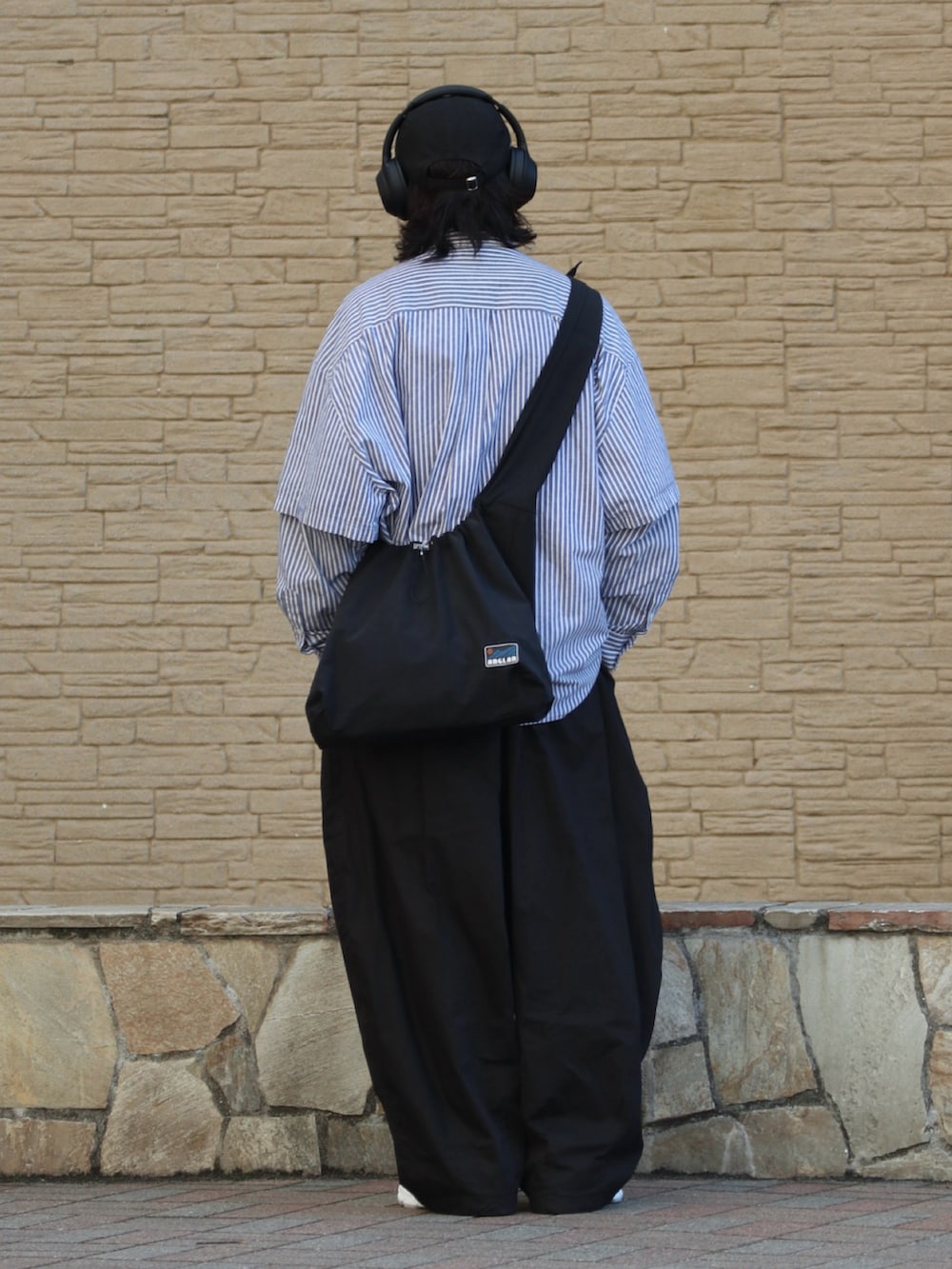 グレー系のスニーカー、ブラック系のチノパンツを着用したメンズの春コーディネートの3枚目の写真