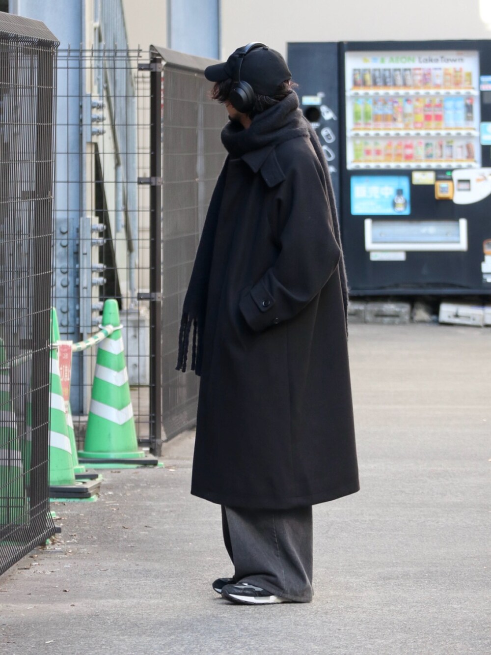 ブラック系のステンカラーコート、グレー系のニット/セーター、ブラック系のデニムパンツを着用したメンズの冬コーディネートの3枚目の写真