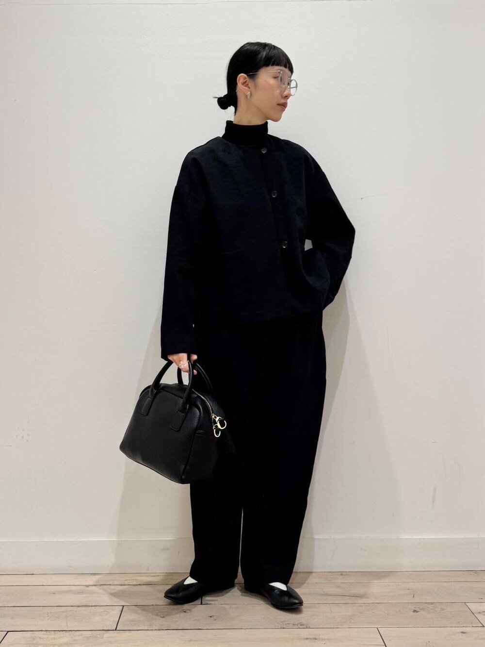 ブラック系のパンプス、ブラック系のボストンバッグ、ブラック系のTシャツ/カットソーを着用したレディースの冬コーディネートの2枚目の写真