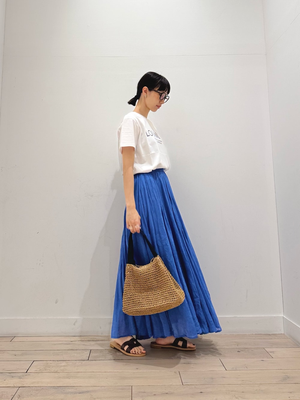 イエロー系のかごバッグ、ホワイト系のTシャツ/カットソー、ブルー系のスカートを着用したレディースの夏コーディネートの2枚目の写真