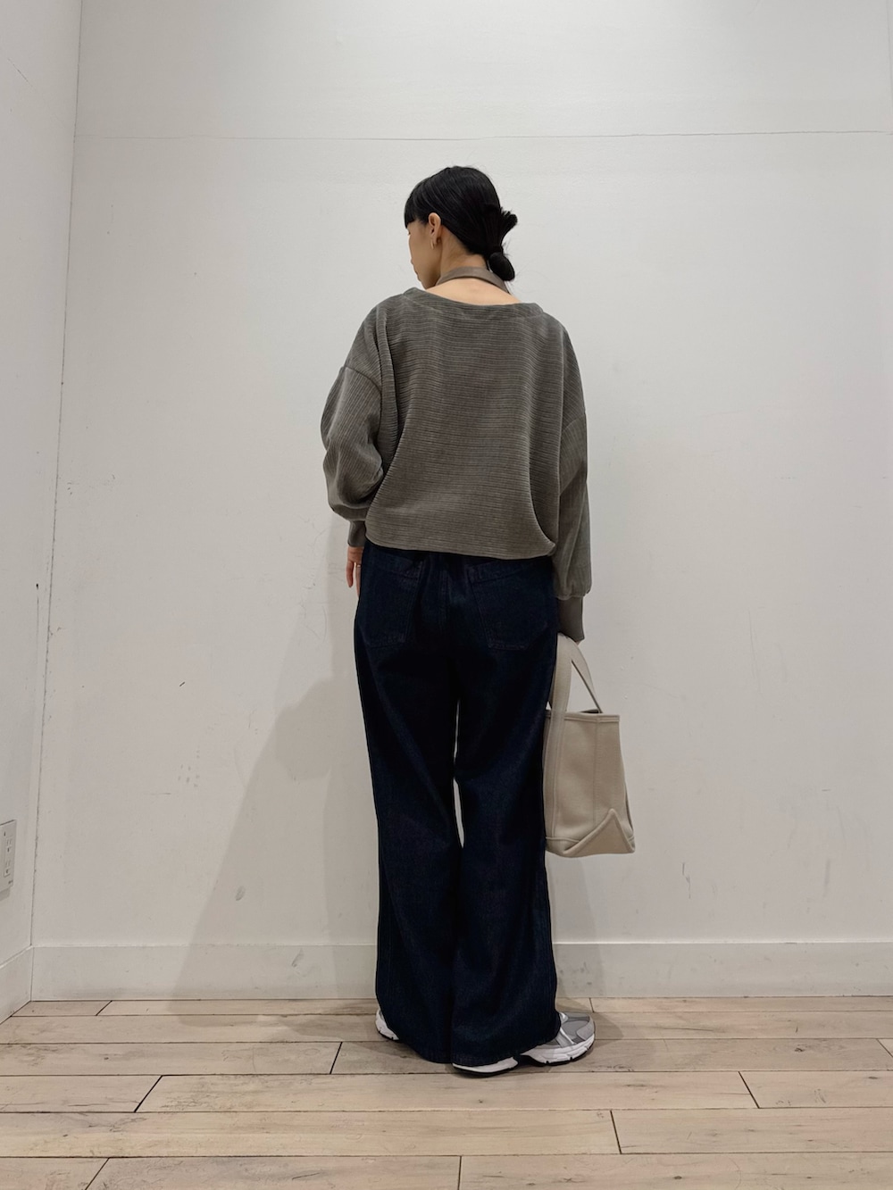 ベージュ系のトートバッグ、グレー系のTシャツ/カットソー、ブルー系のデニムパンツを着用したレディースの冬コーディネートの3枚目の写真