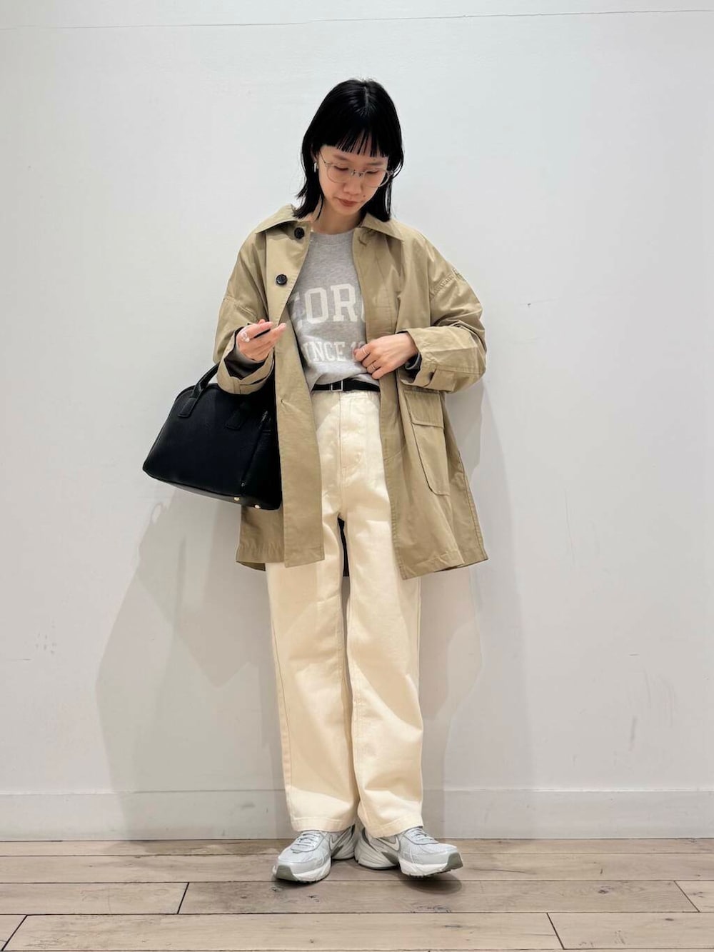 ブラック系のボストンバッグ、シルバー系のスニーカー、ベージュ系のデニムパンツを着用したレディースの冬コーディネートの2枚目の写真