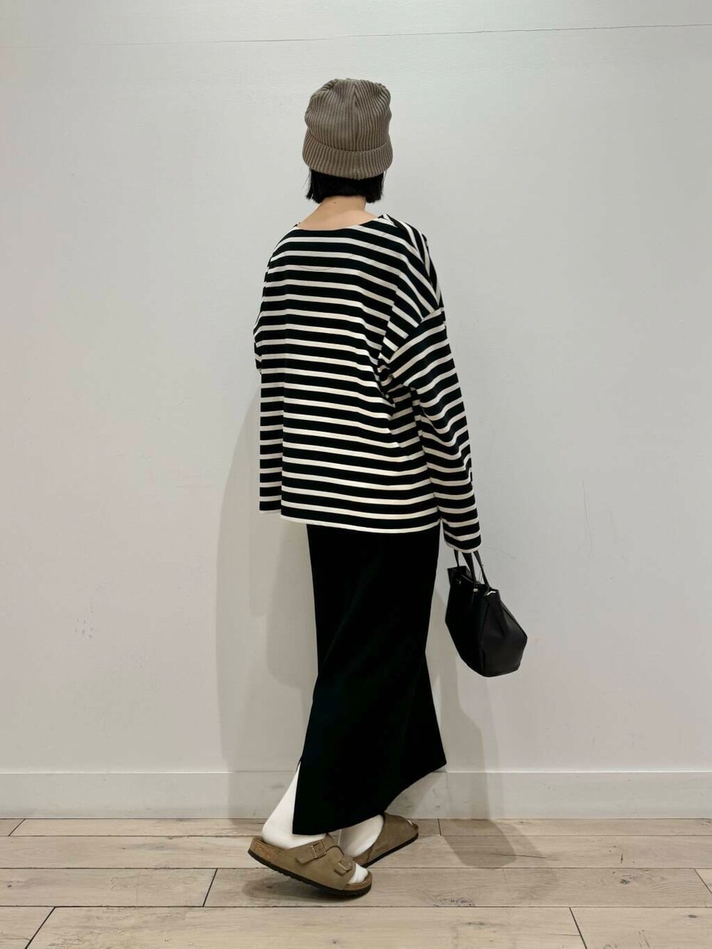 ブラック系のスカート、ベージュ系のサンダル、ブラック系のショルダーバッグを着用したレディースの秋コーディネートの2枚目の写真