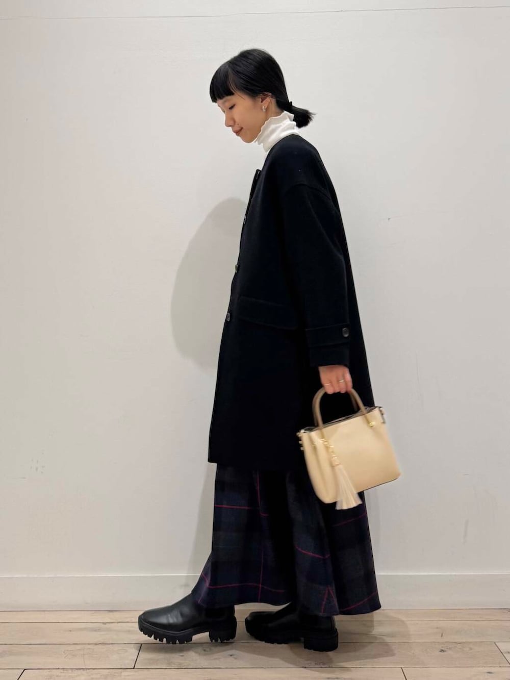 ホワイト系のトートバッグ、ブラック系のノーカラーコート、ブラック系のブーツを着用したレディースの冬コーディネートの2枚目の写真