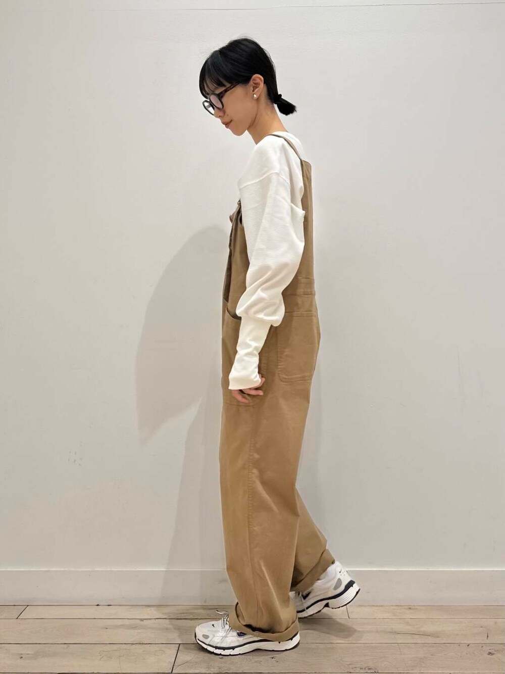 イエロー系のサロペット/オーバーオール、ホワイト系のスニーカー、ホワイト系のTシャツ/カットソーを着用したレディースの秋コーディネートの2枚目の写真