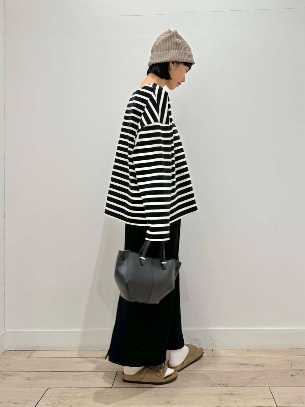 ブラック系のスカート、ベージュ系のサンダル、ブラック系のショルダーバッグを着用したレディースの秋コーディネートの3枚目の写真