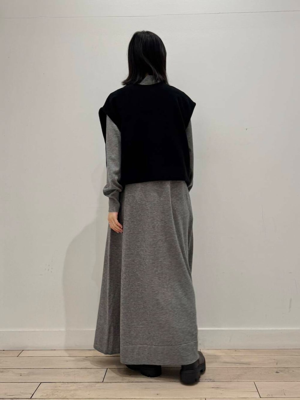 ブラック系のブーツ、グレー系のワンピース、ブラック系のベストを着用したレディースの冬コーディネートの4枚目の写真