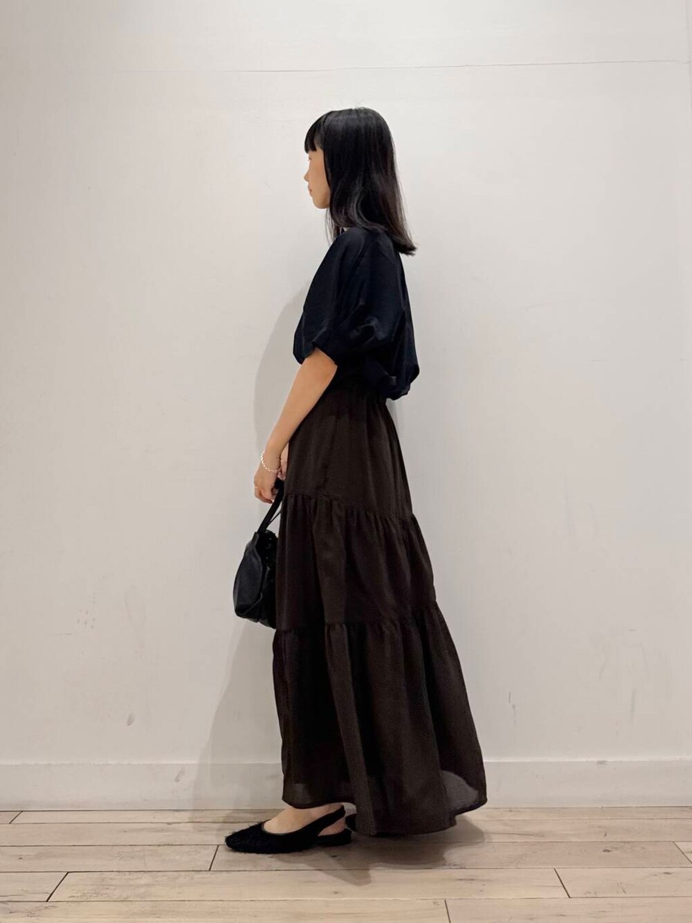 ブラック系のショルダーバッグ、ブラック系のTシャツ/カットソー、ブラウン系のスカートを着用したレディースの夏コーディネートの5枚目の写真