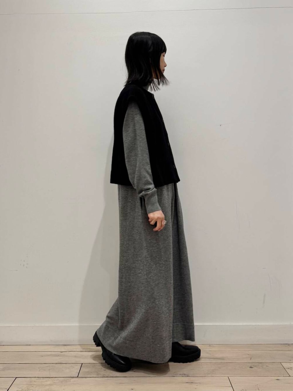 ブラック系のブーツ、グレー系のワンピース、ブラック系のベストを着用したレディースの冬コーディネートの3枚目の写真