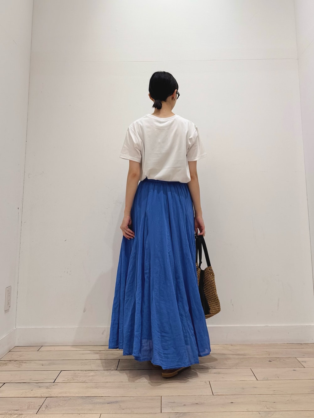 イエロー系のかごバッグ、ホワイト系のTシャツ/カットソー、ブルー系のスカートを着用したレディースの夏コーディネートの3枚目の写真