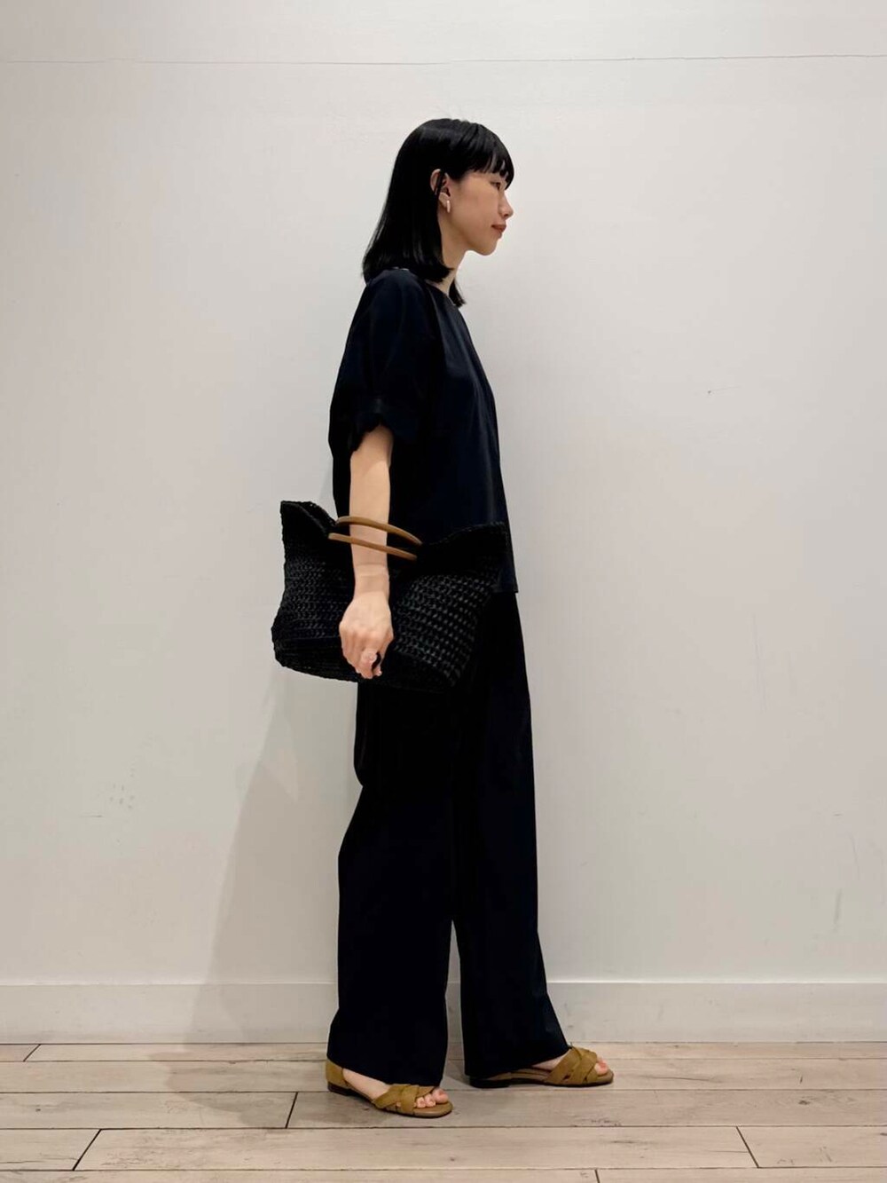 ブラック系のトートバッグ、イエロー系のサンダル、グレー系のその他パンツを着用したレディースの春コーディネートの2枚目の写真