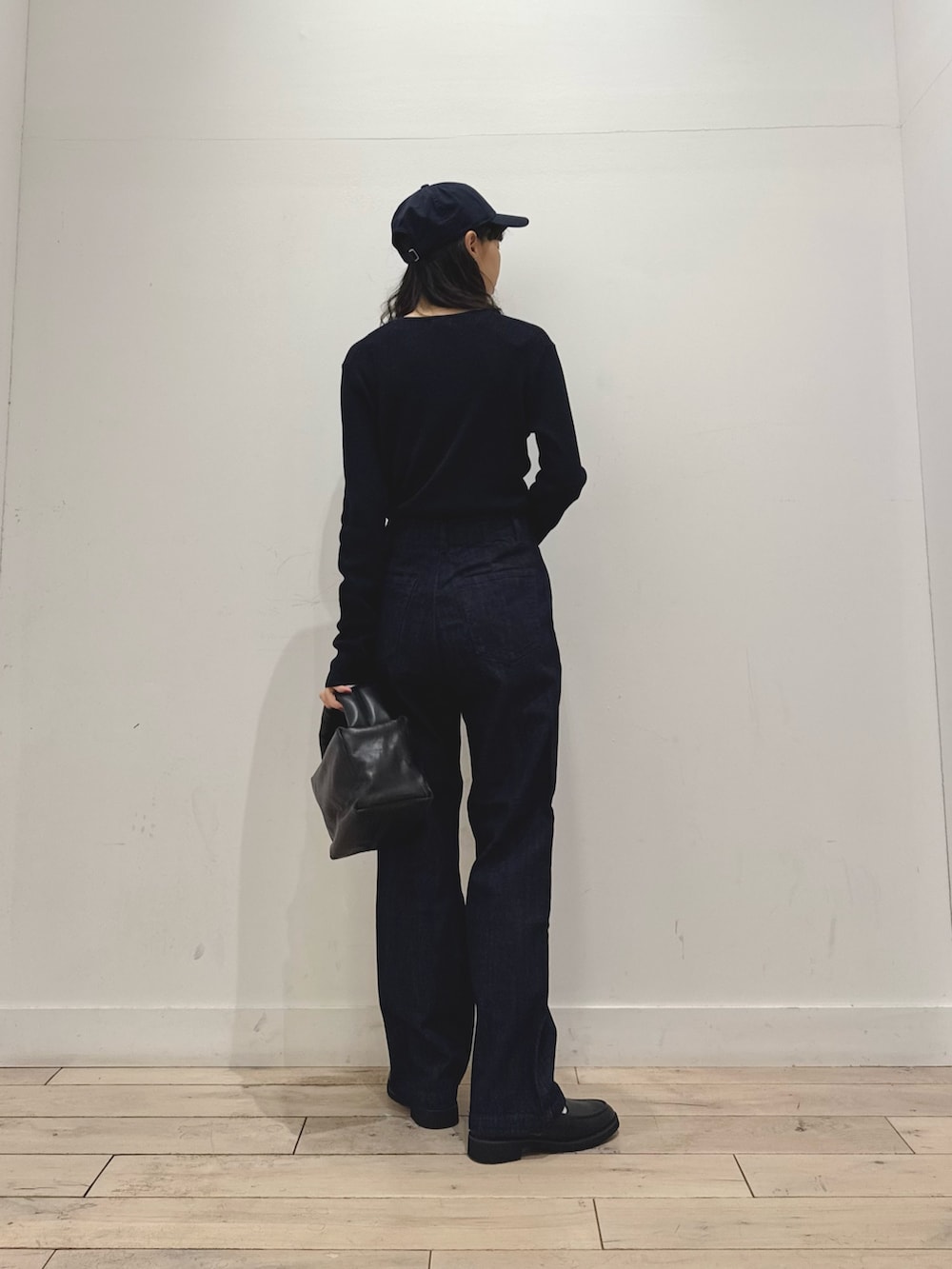 ブルー系のニット/セーター、ブルー系のデニムパンツ、ブラック系のハンドバッグを着用したレディースの秋コーディネートの3枚目の写真