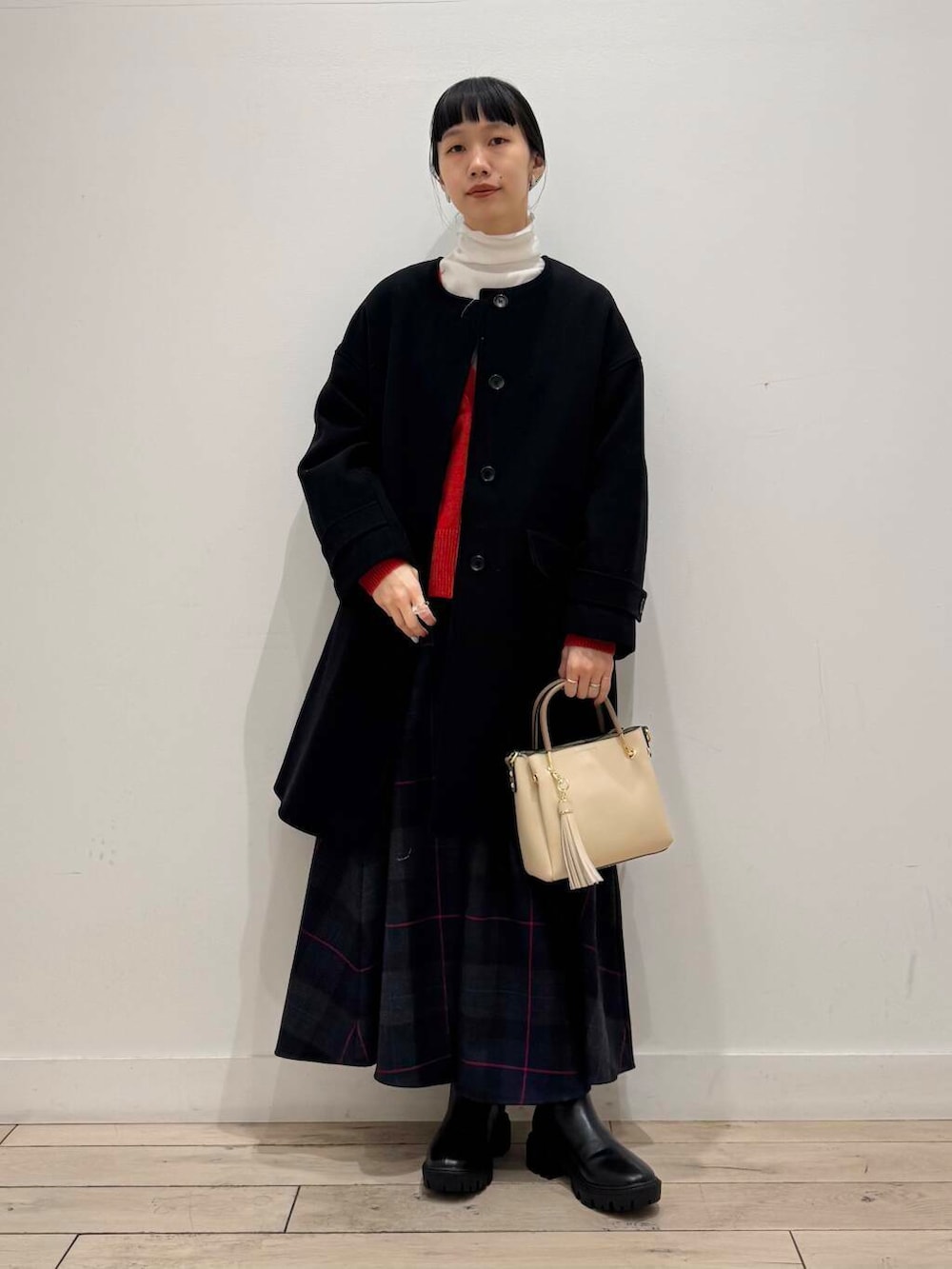 ホワイト系のトートバッグ、ブラック系のノーカラーコート、ブラック系のブーツを着用したレディースの冬コーディネートの5枚目の写真