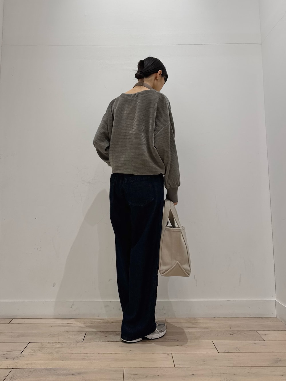 ベージュ系のトートバッグ、グレー系のTシャツ/カットソー、ブルー系のデニムパンツを着用したレディースの冬コーディネートの2枚目の写真