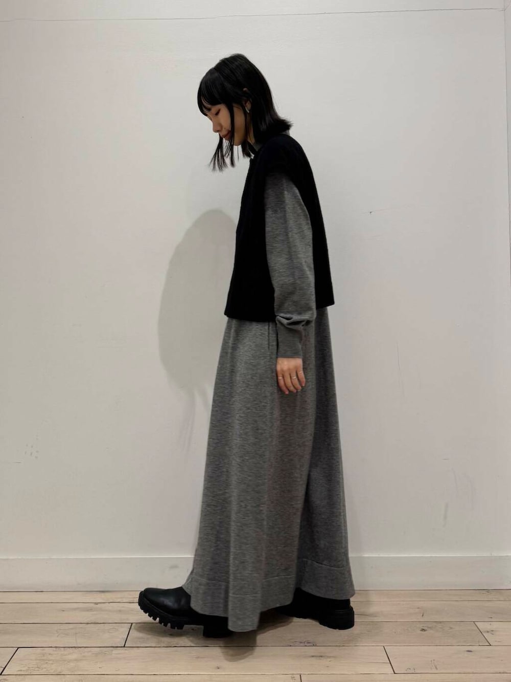 ブラック系のブーツ、グレー系のワンピース、ブラック系のベストを着用したレディースの冬コーディネートの2枚目の写真