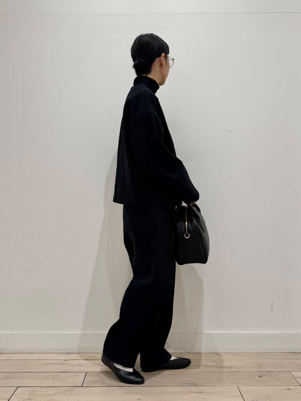ブラック系のパンプス、ブラック系のボストンバッグ、ブラック系のTシャツ/カットソーを着用したレディースの冬コーディネートの3枚目の写真