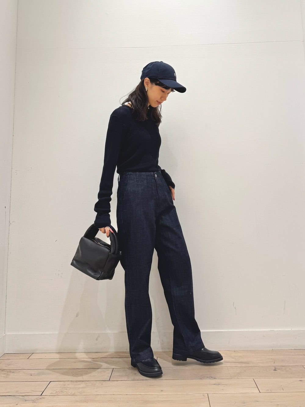 ブルー系のニット/セーター、ブルー系のデニムパンツ、ブラック系のハンドバッグを着用したレディースの秋コーディネートの2枚目の写真