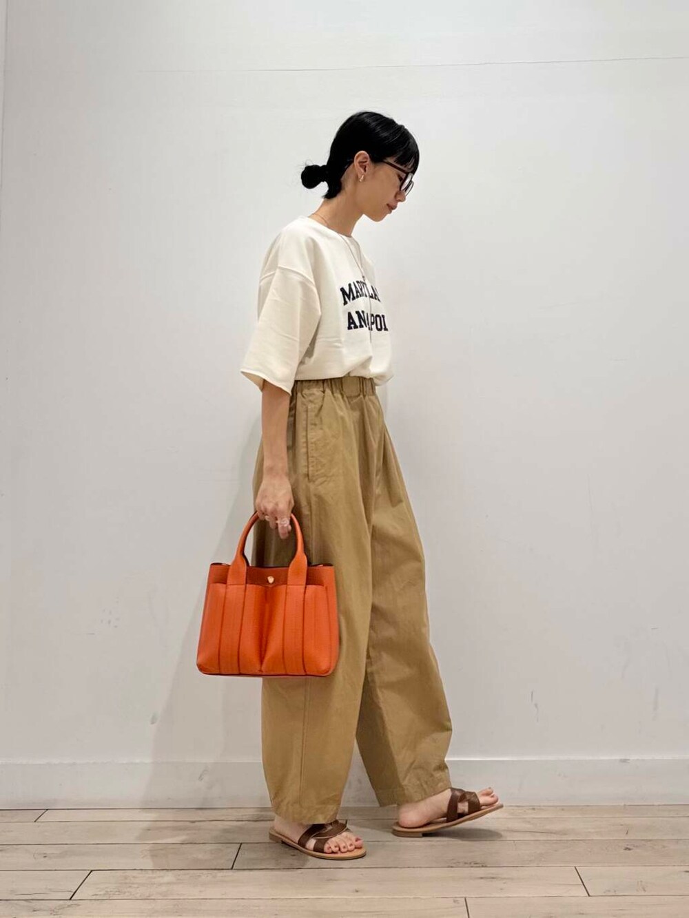 ブラウン系のサンダル、ベージュ系のその他パンツ、オレンジ系のトートバッグを着用したレディースの夏コーディネートの2枚目の写真
