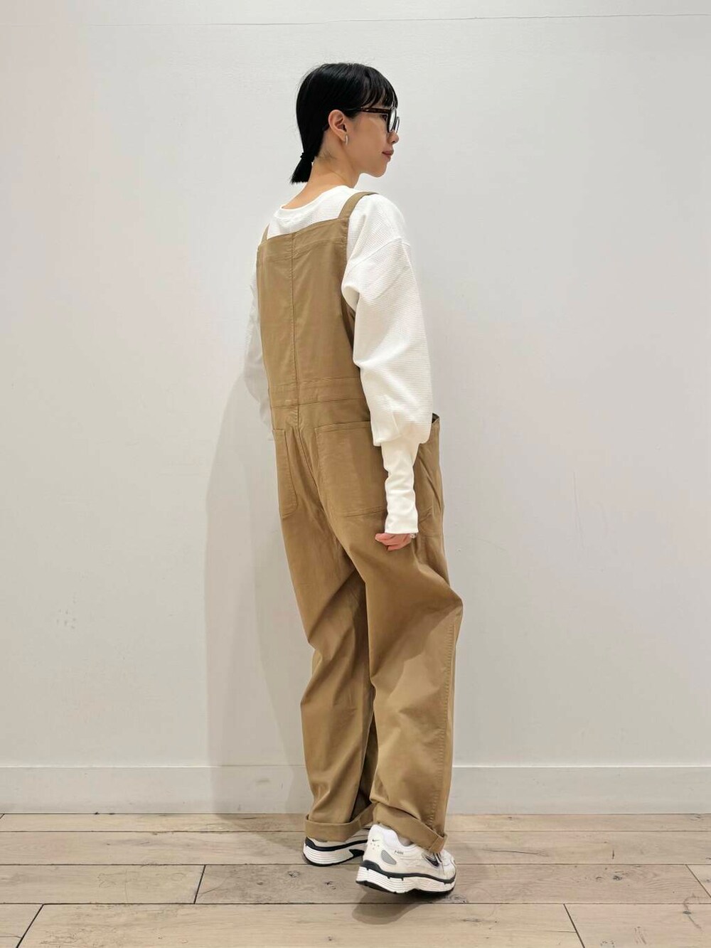 イエロー系のサロペット/オーバーオール、ホワイト系のスニーカー、ホワイト系のTシャツ/カットソーを着用したレディースの秋コーディネートの4枚目の写真