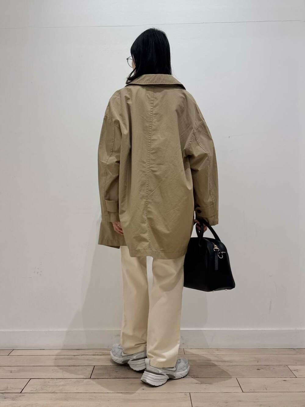 ブラック系のボストンバッグ、シルバー系のスニーカー、ベージュ系のデニムパンツを着用したレディースの冬コーディネートの4枚目の写真