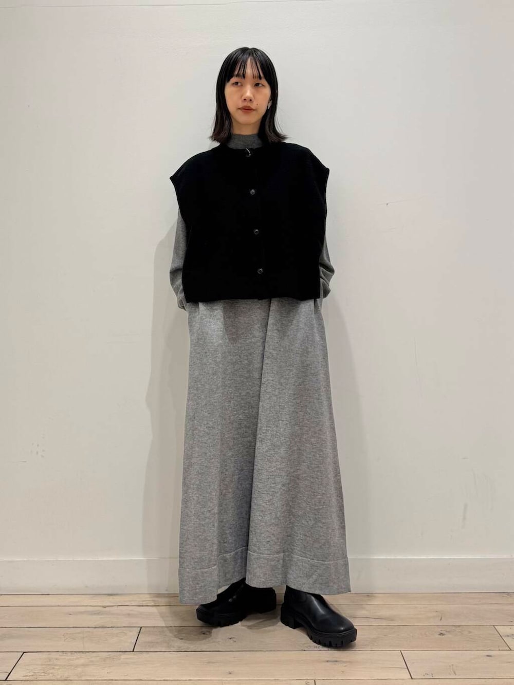 ブラック系のブーツ、グレー系のワンピース、ブラック系のベストを着用したレディースの冬コーディネートの5枚目の写真