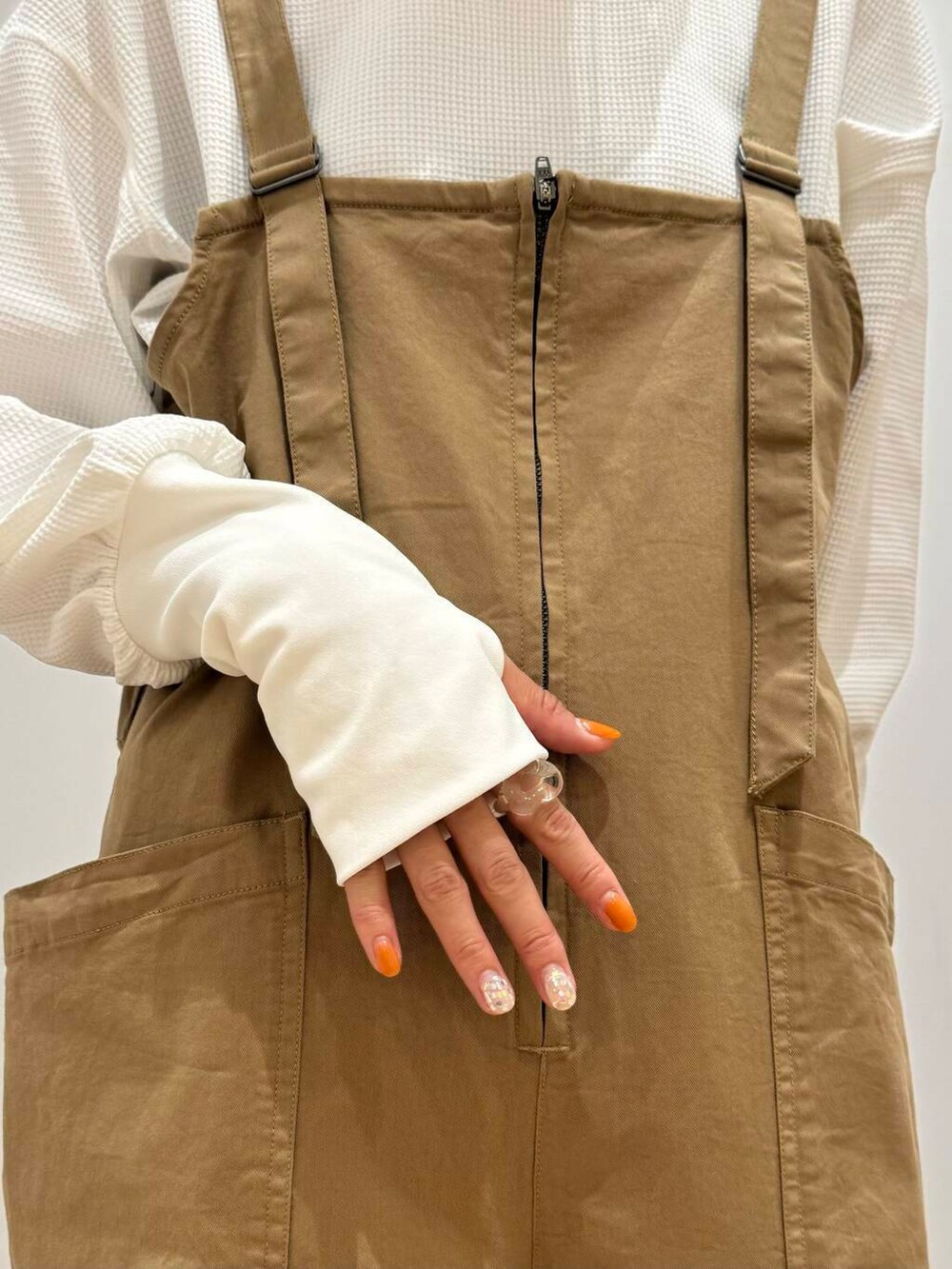 イエロー系のサロペット/オーバーオール、ホワイト系のスニーカー、ホワイト系のTシャツ/カットソーを着用したレディースの秋コーディネートの6枚目の写真