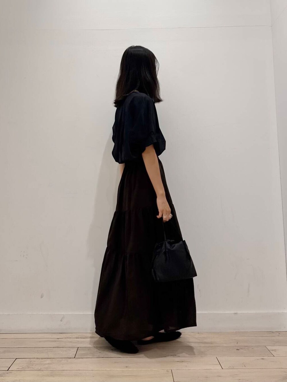 ブラック系のショルダーバッグ、ブラック系のTシャツ/カットソー、ブラウン系のスカートを着用したレディースの夏コーディネートの3枚目の写真