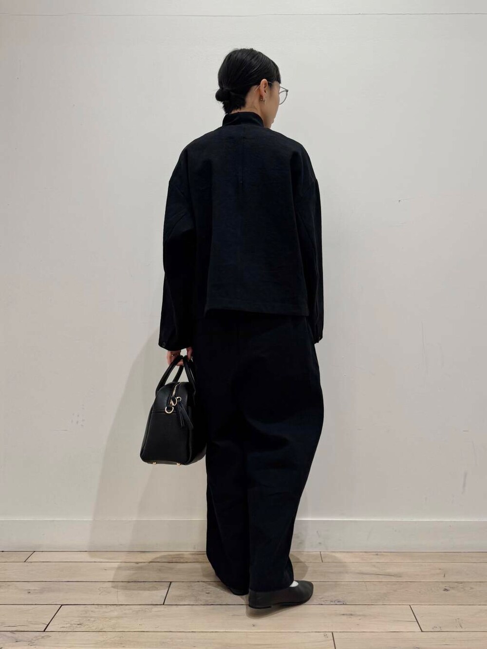 ブラック系のパンプス、ブラック系のボストンバッグ、ブラック系のTシャツ/カットソーを着用したレディースの冬コーディネートの4枚目の写真