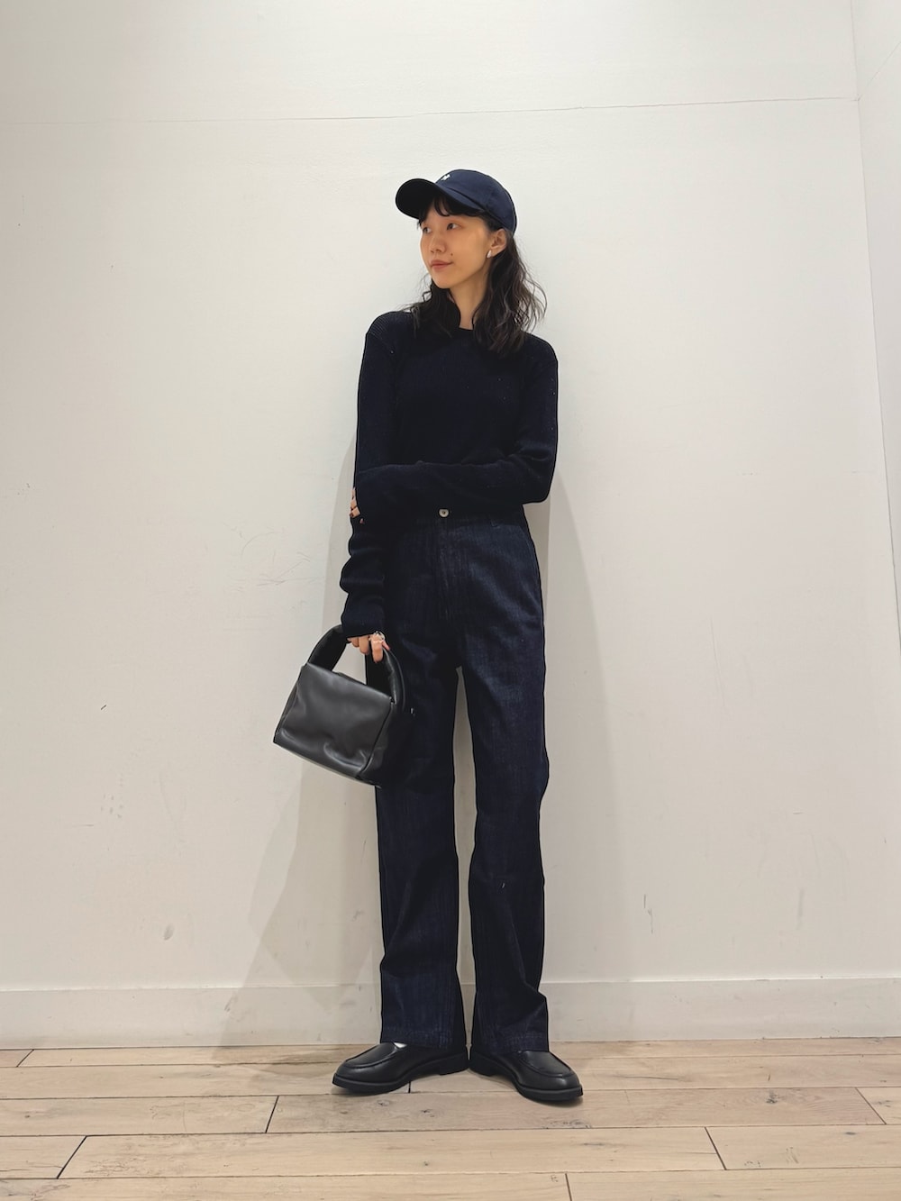 ブルー系のニット/セーター、ブルー系のデニムパンツ、ブラック系のハンドバッグを着用したレディースの秋コーディネートの4枚目の写真