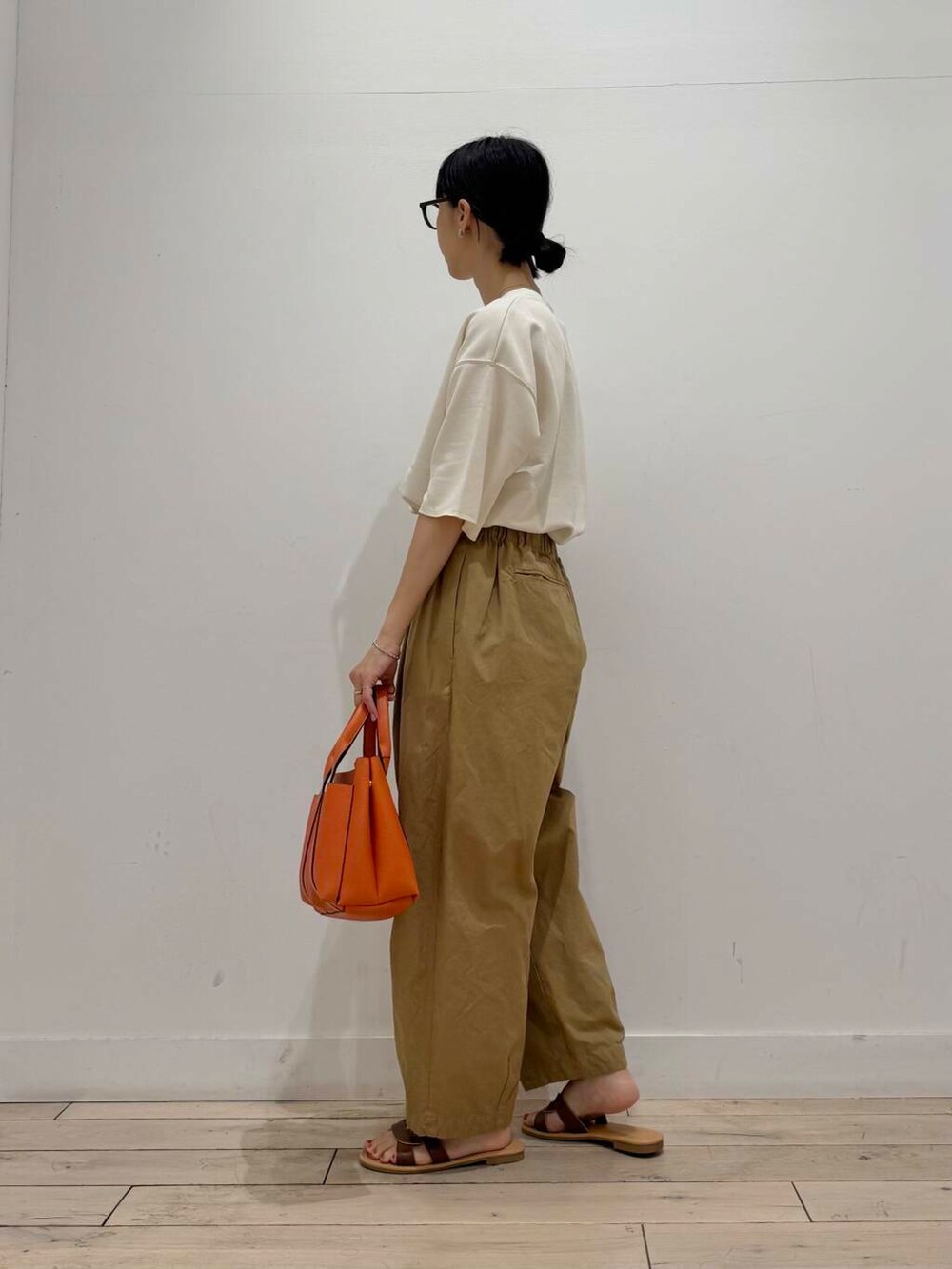 ブラウン系のサンダル、ベージュ系のその他パンツ、オレンジ系のトートバッグを着用したレディースの夏コーディネートの4枚目の写真