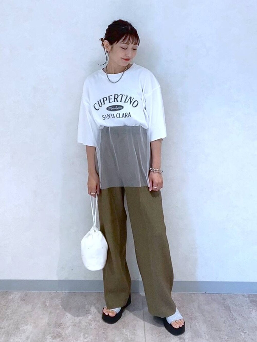 シルバー系のサンダル、ホワイト系のショルダーバッグ、ブラウン系のスラックスを着用したレディースの夏コーディネートの2枚目の写真