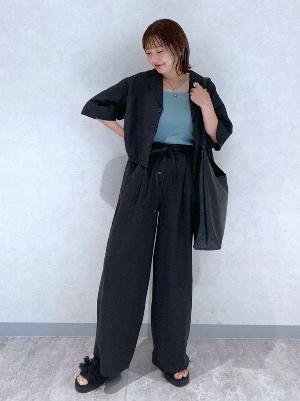 ブラック系のサンダル、ブラック系のショルダーバッグ、ブルー系のタンクトップを着用したレディースの春コーディネートの2枚目の写真