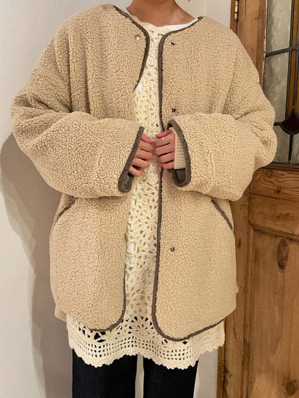 ブルー系のデニムパンツ、ホワイト系のニット/セーター、グリーン系のノーカラーコートを着用したレディースの冬コーディネートの2枚目の写真
