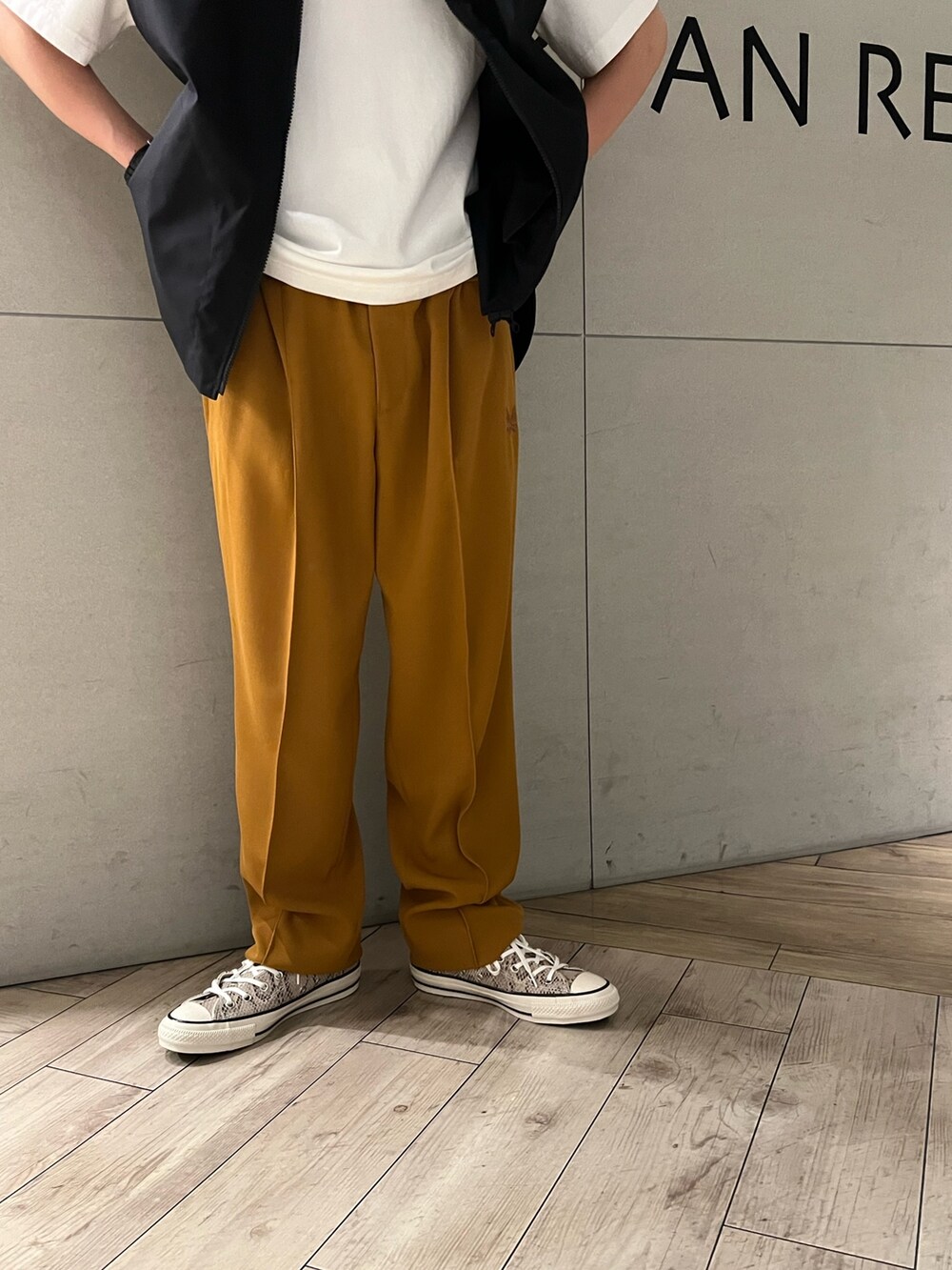 ホワイト系のTシャツ/カットソー、オレンジ系のスラックス、その他のスニーカーを着用したメンズの春コーディネートの3枚目の写真