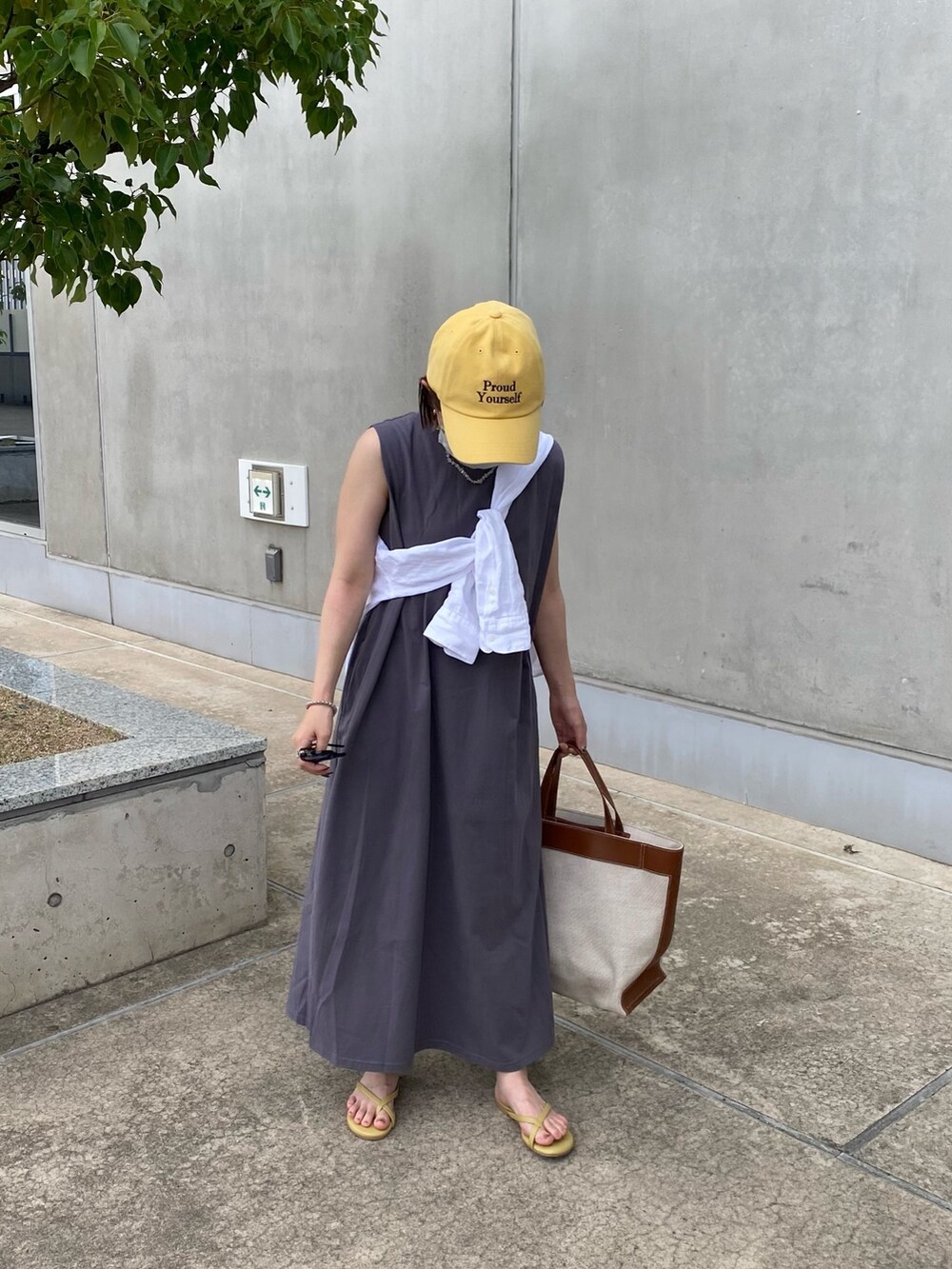 イエロー系のトートバッグ、グレー系のワンピース、イエロー系のサンダルを着用したレディースの夏コーディネートの2枚目の写真