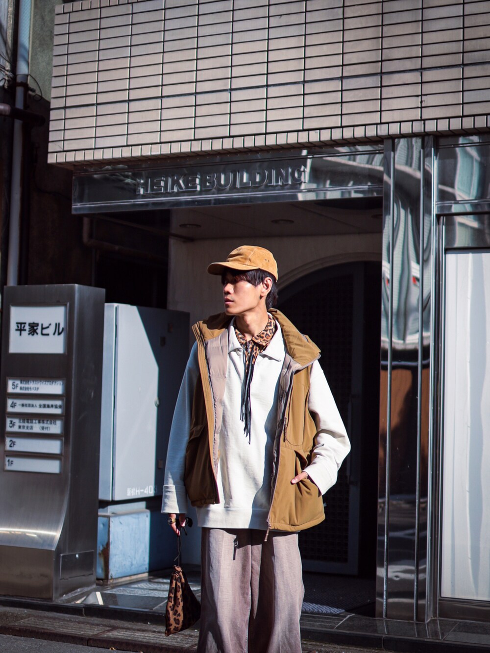 ブラウン系のハンドバッグ、ブラウン系のシャツ/ブラウス、ブラウン系のキャップを着用したメンズの秋コーディネートの3枚目の写真