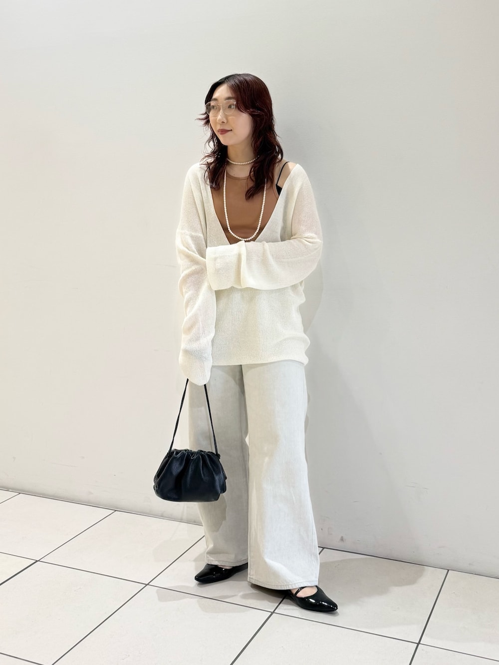 ブラック系のパンプス、オレンジ系のタンクトップ、ホワイト系のニット/セーターを着用したレディースの春コーディネートの2枚目の写真