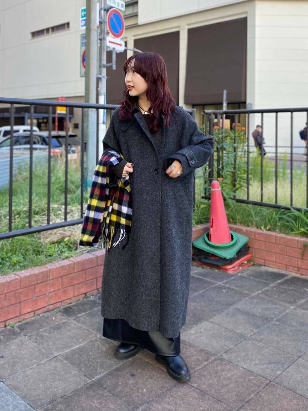 ブラック系のステンカラーコート、グリーン系のニット/セーター、ブラック系のブーツを着用したレディースの秋コーディネートの2枚目の写真