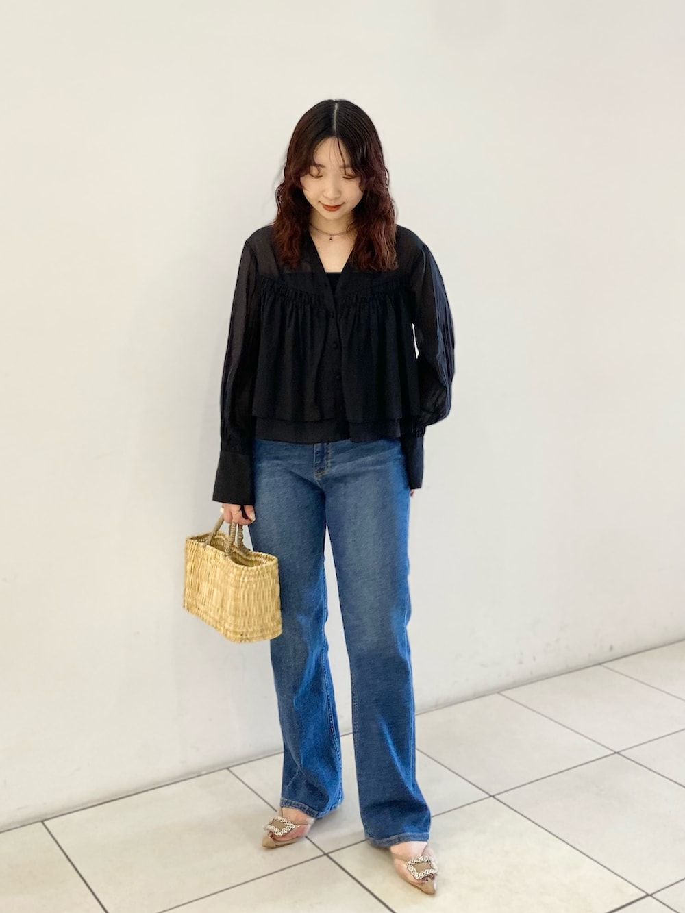 ブラック系のシャツ/ブラウス、ベージュ系のハンドバッグ、ブルー系のデニムパンツを着用したレディースの春コーディネートの2枚目の写真