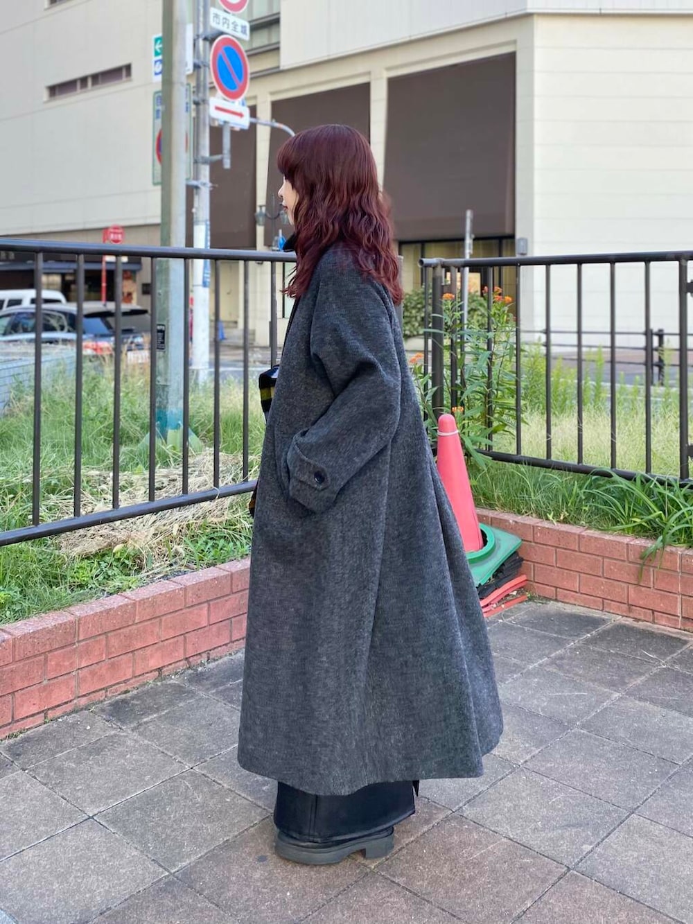 ブラック系のステンカラーコート、グリーン系のニット/セーター、ブラック系のブーツを着用したレディースの秋コーディネートの3枚目の写真