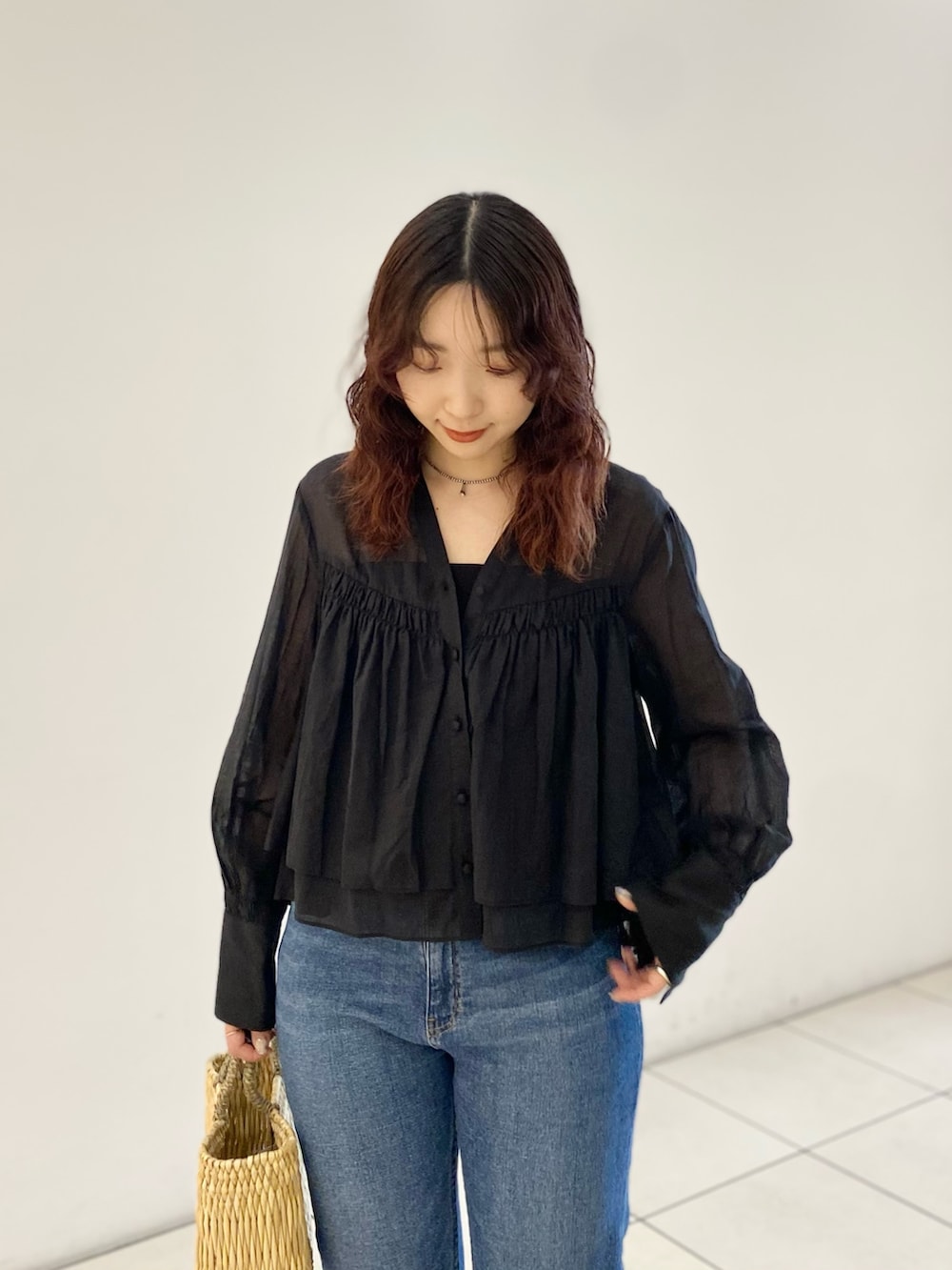 ブラック系のシャツ/ブラウス、ベージュ系のハンドバッグ、ブルー系のデニムパンツを着用したレディースの春コーディネートの6枚目の写真