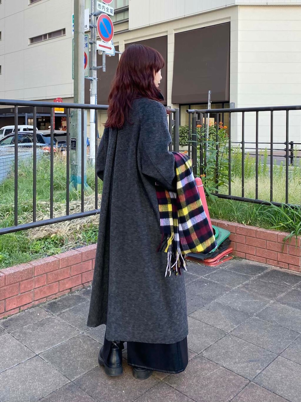 ブラック系のステンカラーコート、グリーン系のニット/セーター、ブラック系のブーツを着用したレディースの秋コーディネートの4枚目の写真