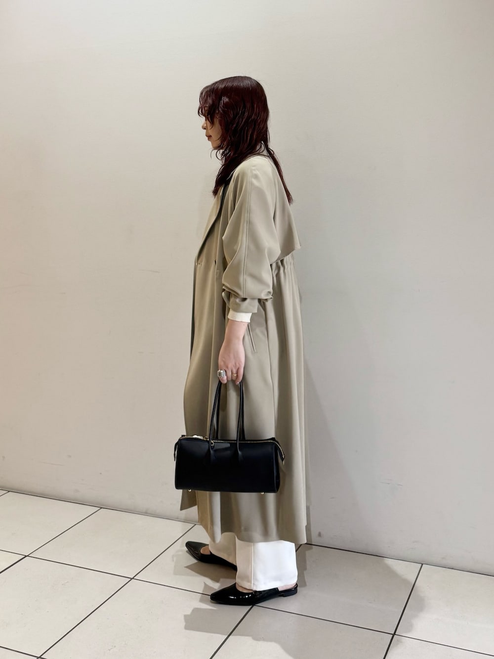 ベージュ系のトレンチコート、ホワイト系のニット/セーター、ブルー系のシャツ/ブラウスを着用したレディースの冬コーディネートの4枚目の写真