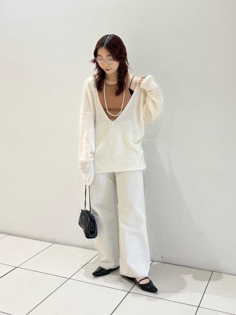 ブラック系のパンプス、オレンジ系のタンクトップ、ホワイト系のニット/セーターを着用したレディースの春コーディネートの3枚目の写真