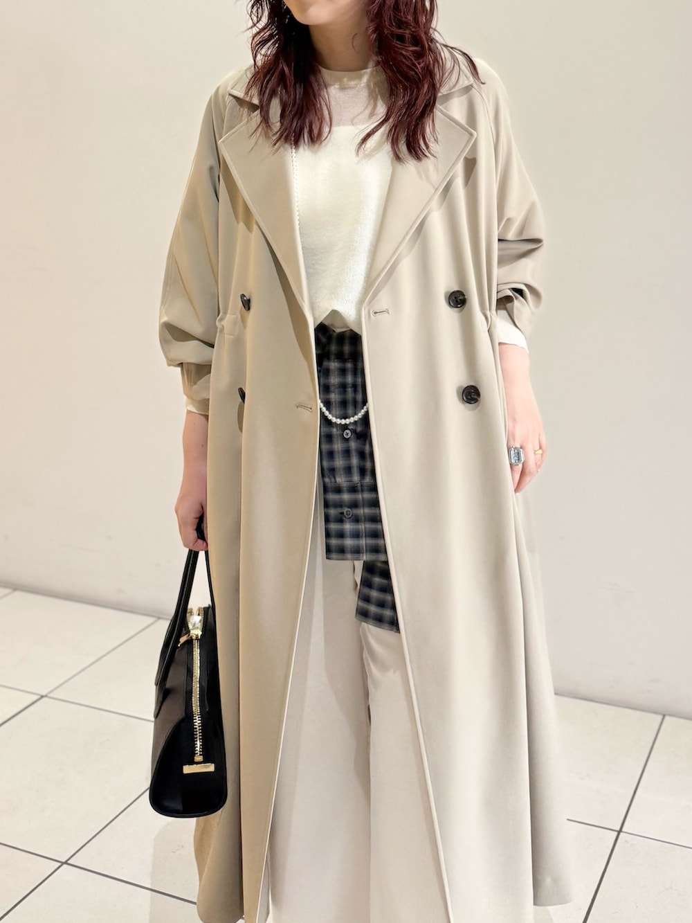 ベージュ系のトレンチコート、ホワイト系のニット/セーター、ブルー系のシャツ/ブラウスを着用したレディースの冬コーディネートの7枚目の写真